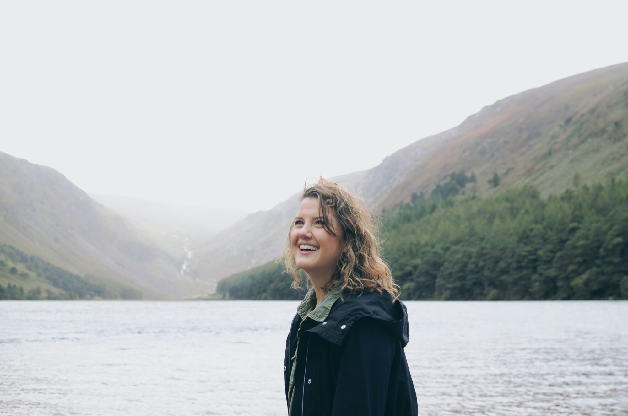 woman smiling with water and mountains behind her