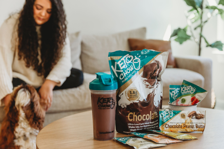 woman and dog sitting with Keto Chow on table