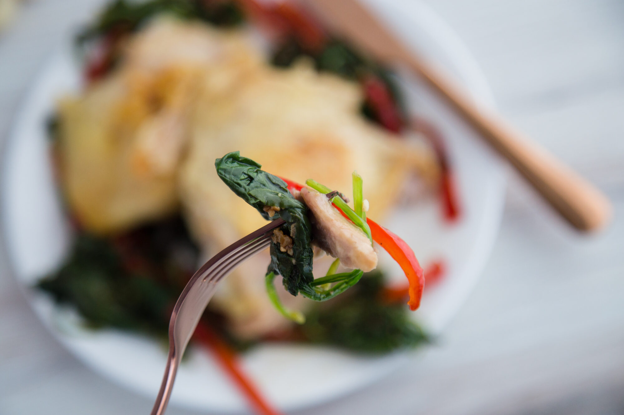 Close up-chicken, spinach and red pepper on a fork.