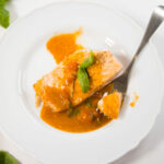 Top view - Salmon with tomato basil sauce on a white plate with a fork.