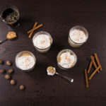 Top view - Four dessert cups filled with with Pumpkin Spice Latte Peanut Butter Mousse, topped with whipped cream. Cinnamon sticks on the side.