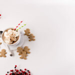 Top view - White mug filled with Hot Gingerbread Cocoa, topped with whipped cream. Gingerbread cookies to the side.