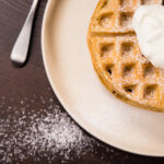 Top view - two Irish Cream Belgian Waffles, topped with whipped cream.