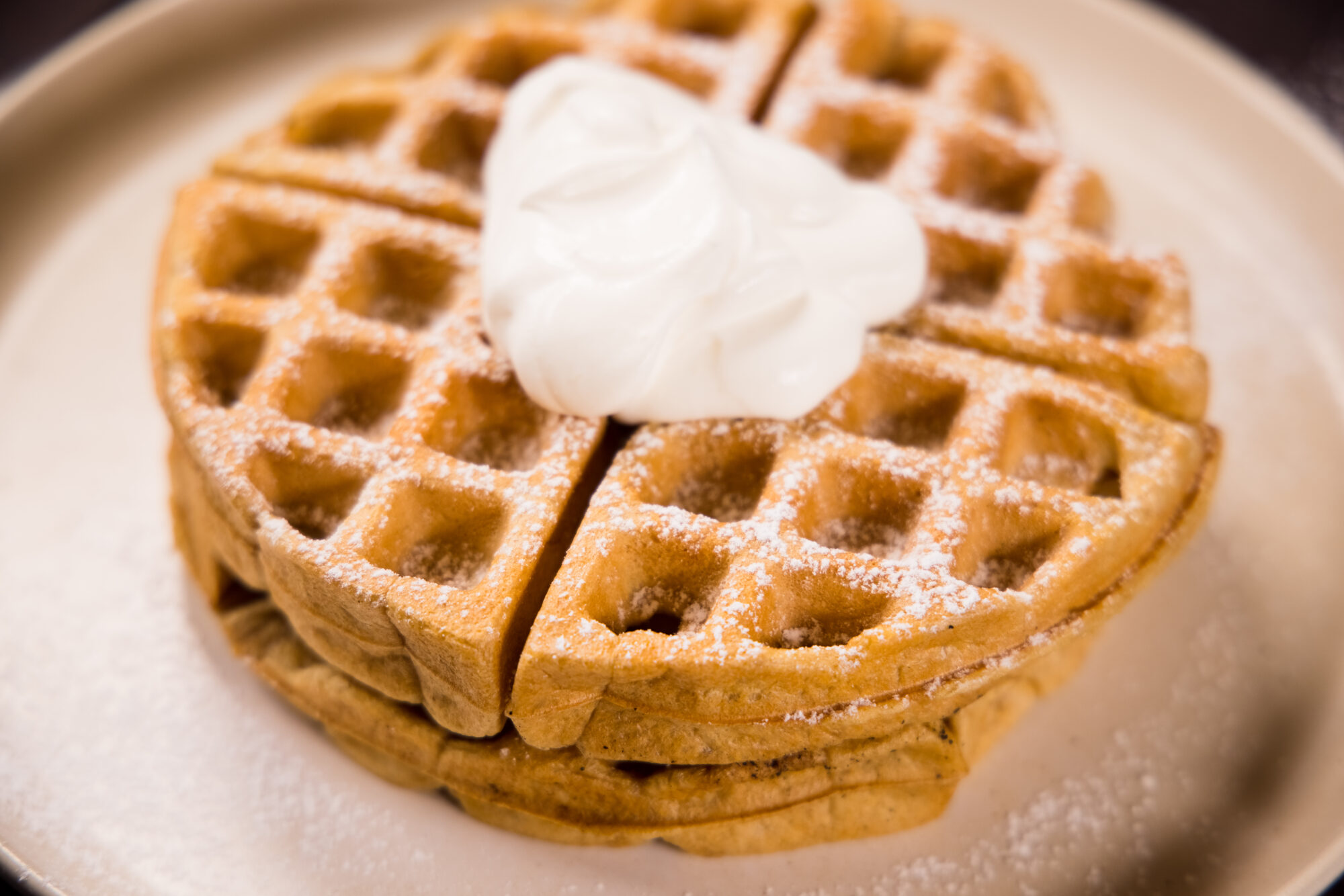 Close up - two Irish Cream Belgian Waffles, topped with whipped cream.