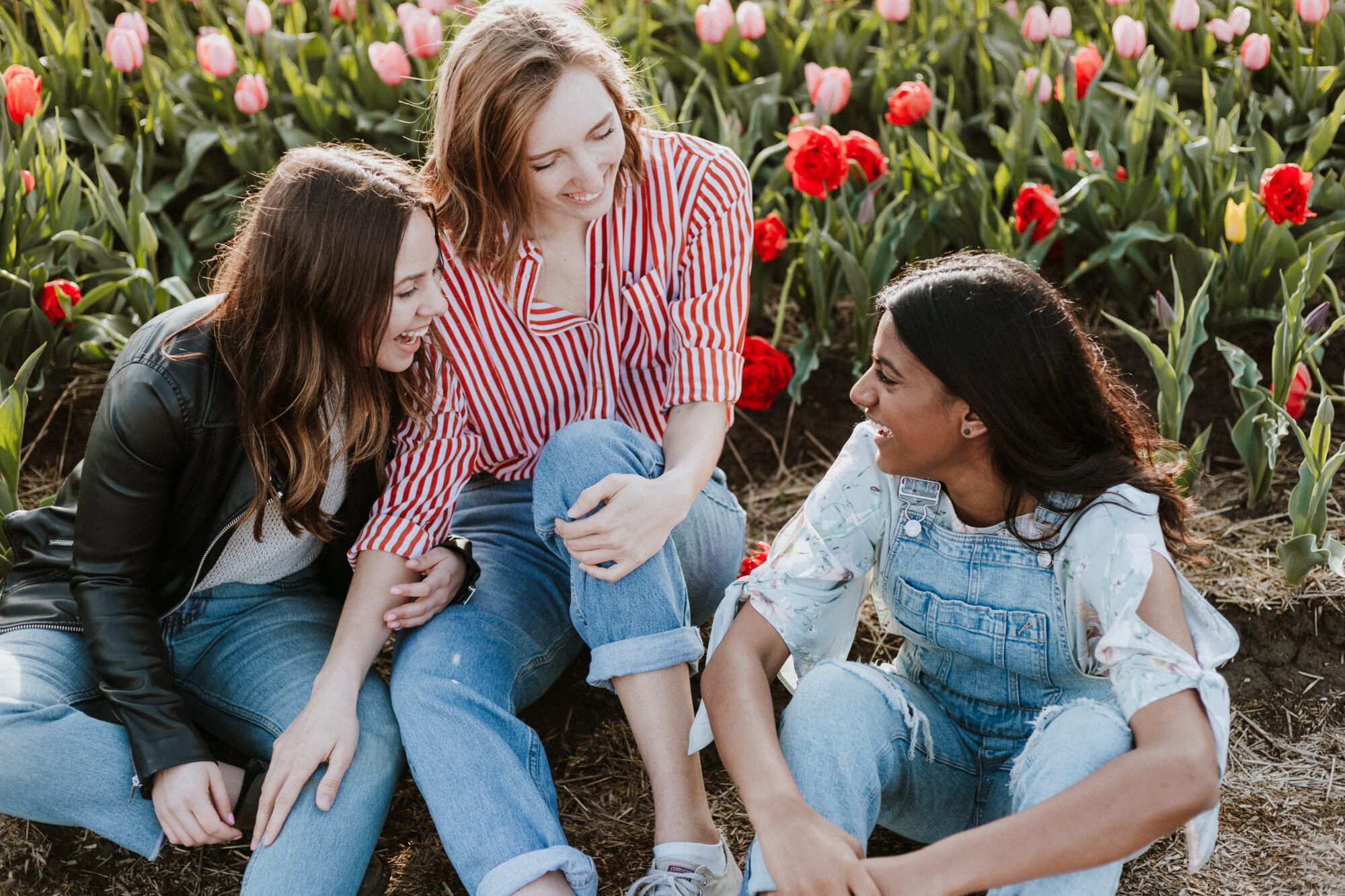 group of women smiling in front of flowers