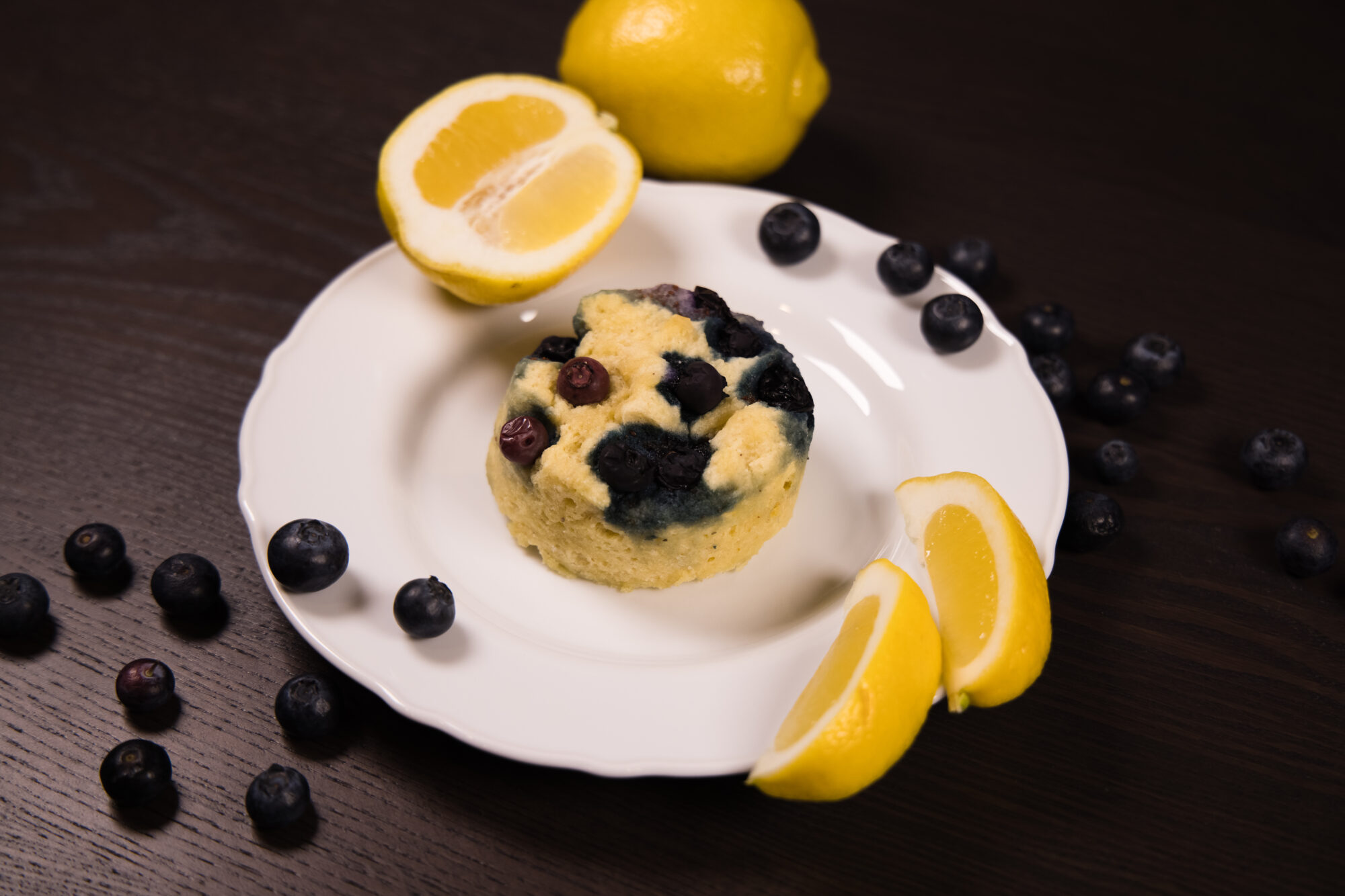 Close up - Lemon Blueberry Mug Cake with lemon wedges on the side.