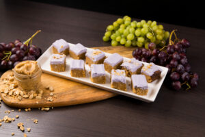 White tray with squares of Peanut Butter Blondies with Grape Frosting.