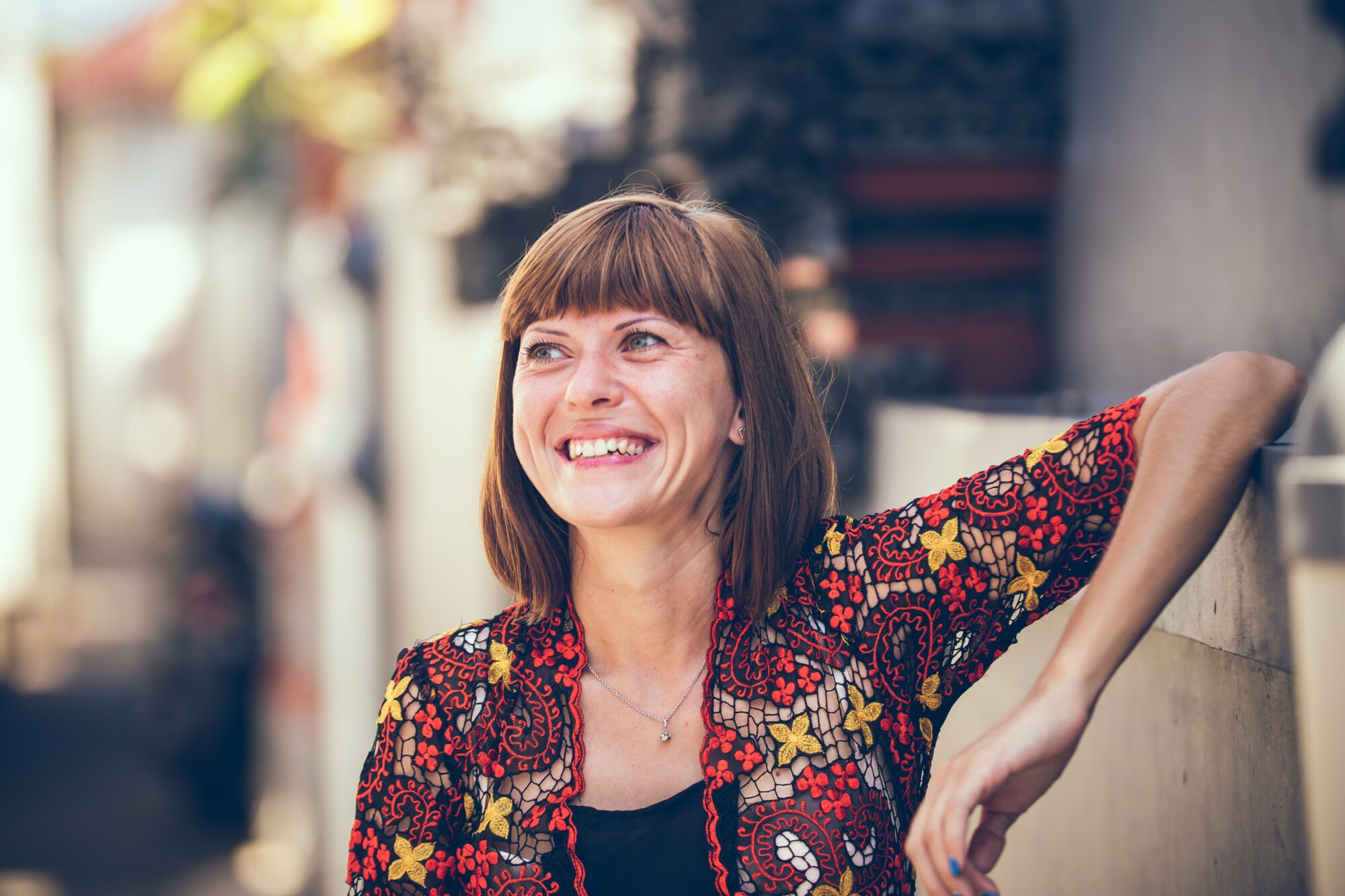 woman smiling while leaning on wall