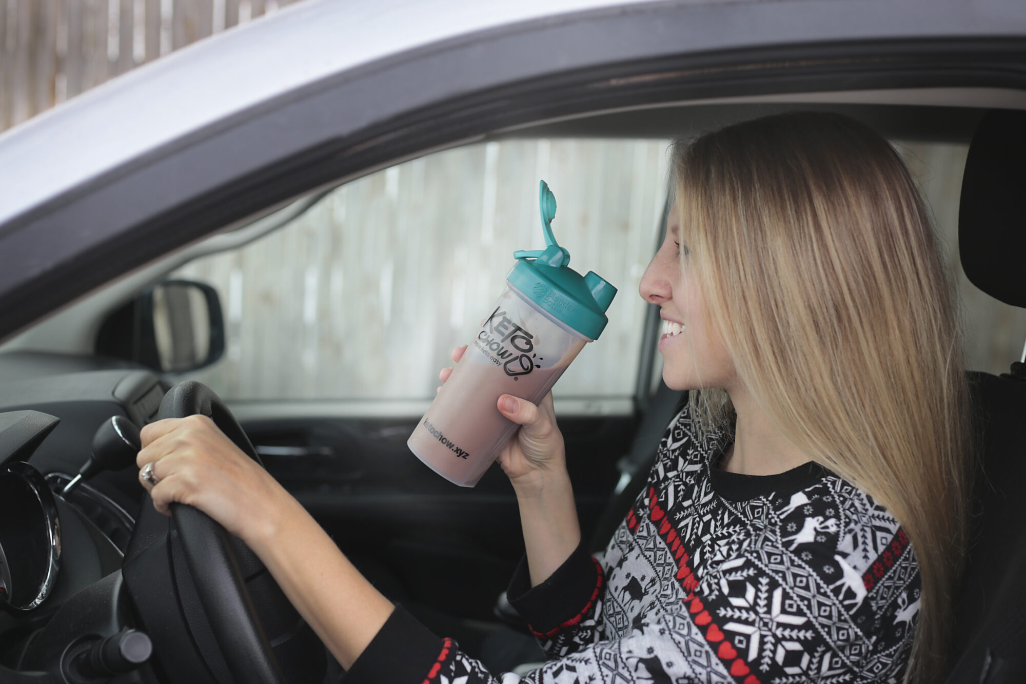 woman holding Keto Chow while driving a car