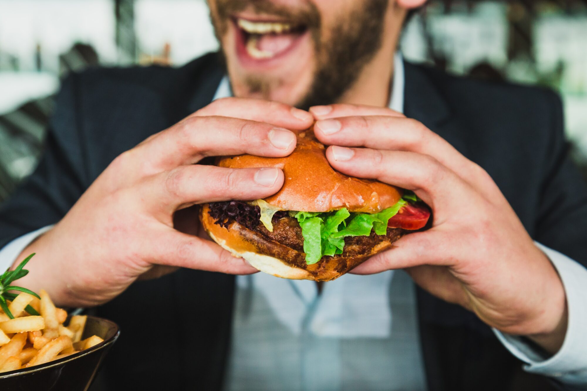 man eating a burger with fries