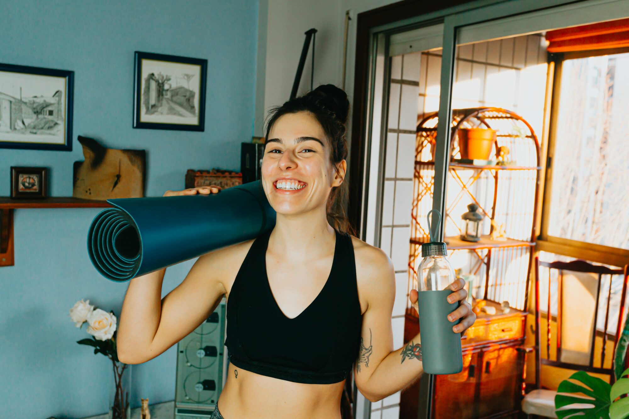 woman smiling while holding yoga mat