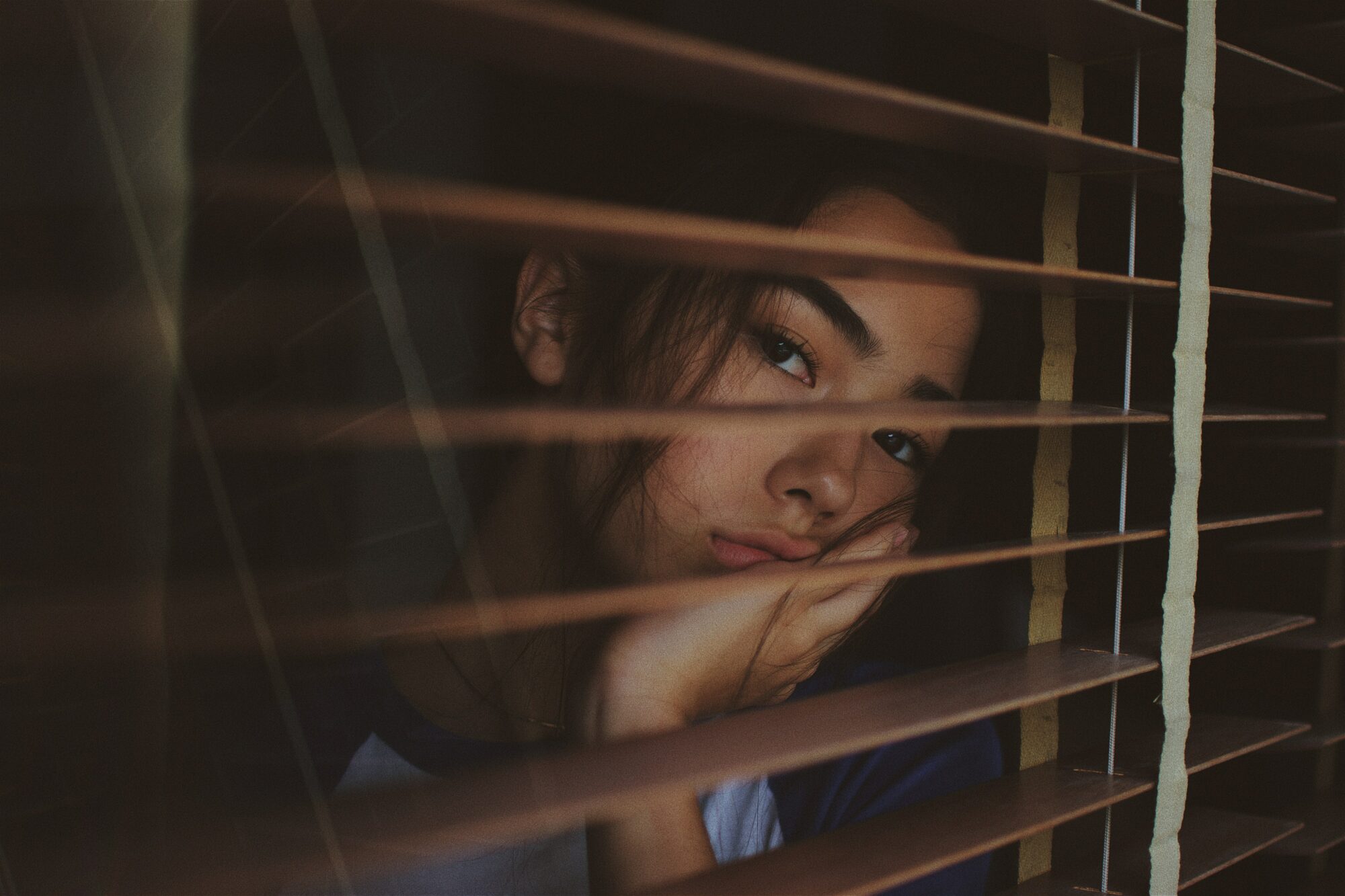 woman looking through blinds