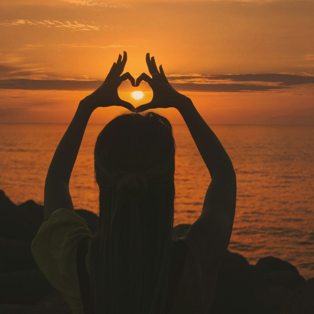 woman holding up hands in shape of heart