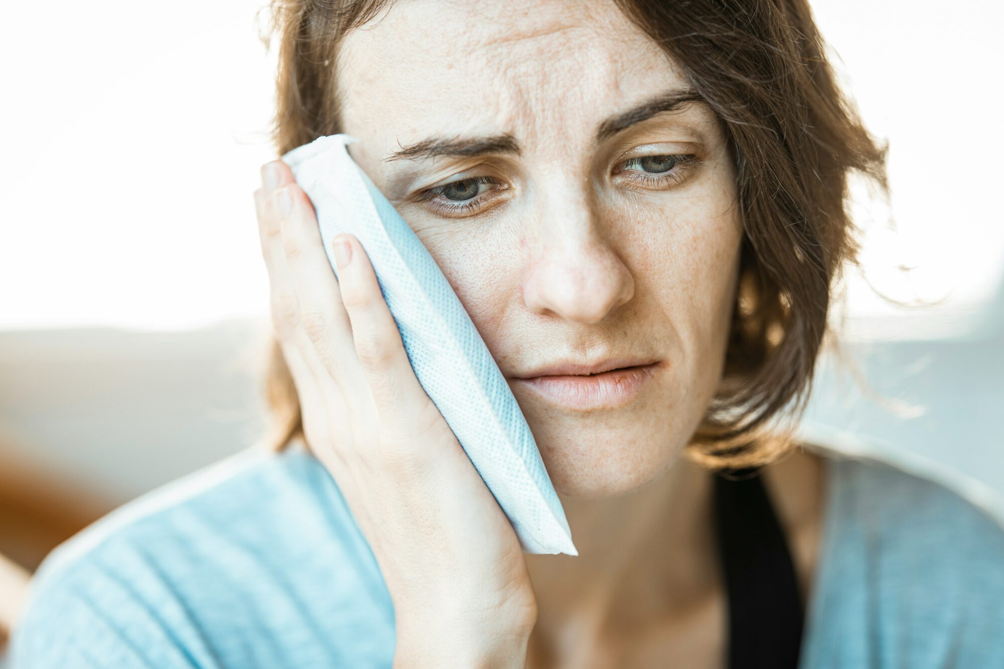 woman holding ice to cheek