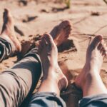 two pairs of feet on beach