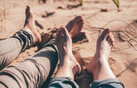 two pairs of feet on beach