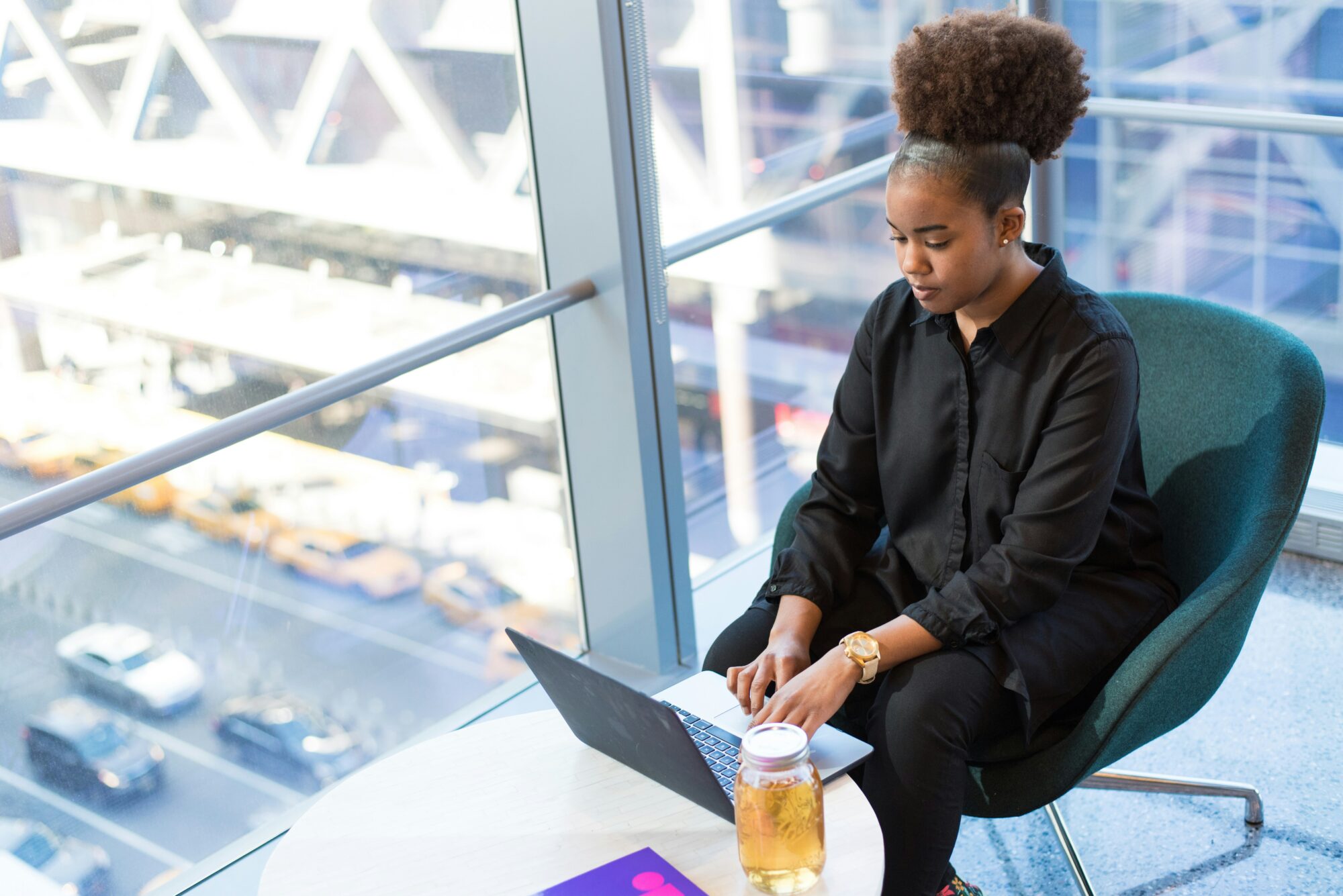 woman typing on computer with drink on table