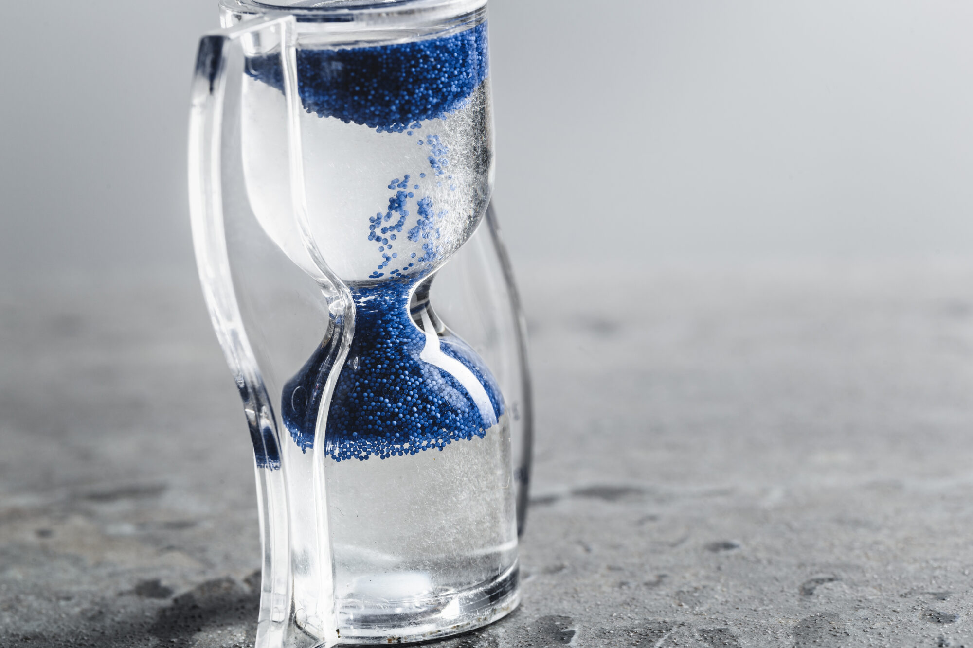 Closeup of hourglass on an uneven sandy surface