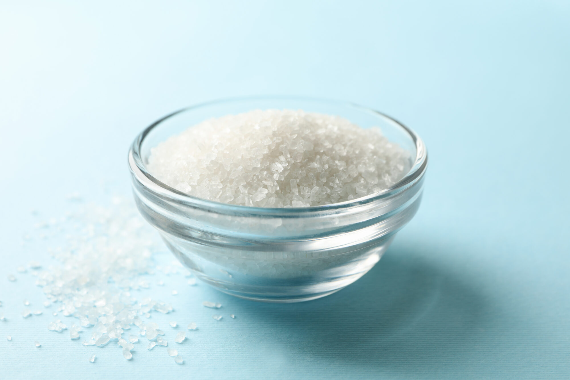 Glass bowl of salt on blue background